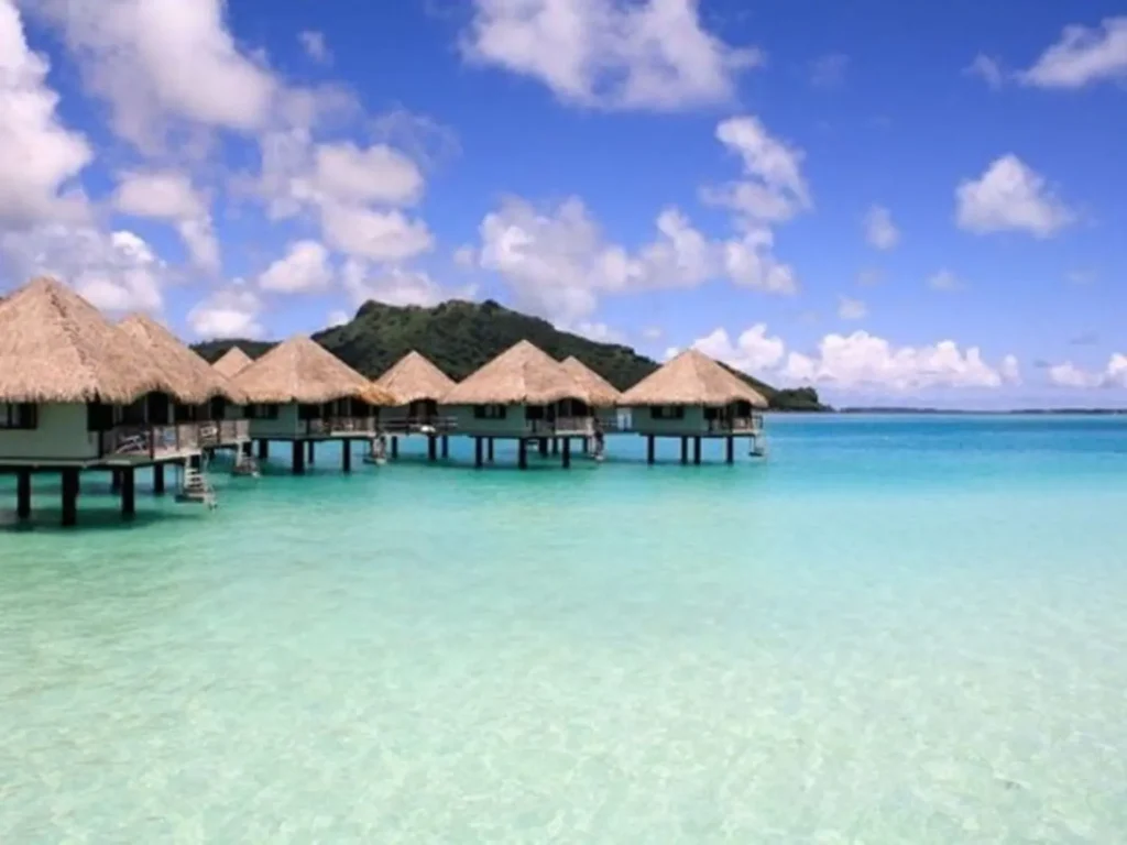 Paisaje de islas vulnerables al cambio climático en el Pacífico con búngalos sobre el agua.