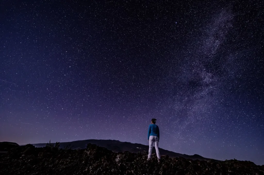 cielos-oscuros | Ambienta - Staging Mujer observando la Vía Láctea bajo los cielos oscuros en Mauna Loa, Hawaii. Fotografía de Youli Zhao.