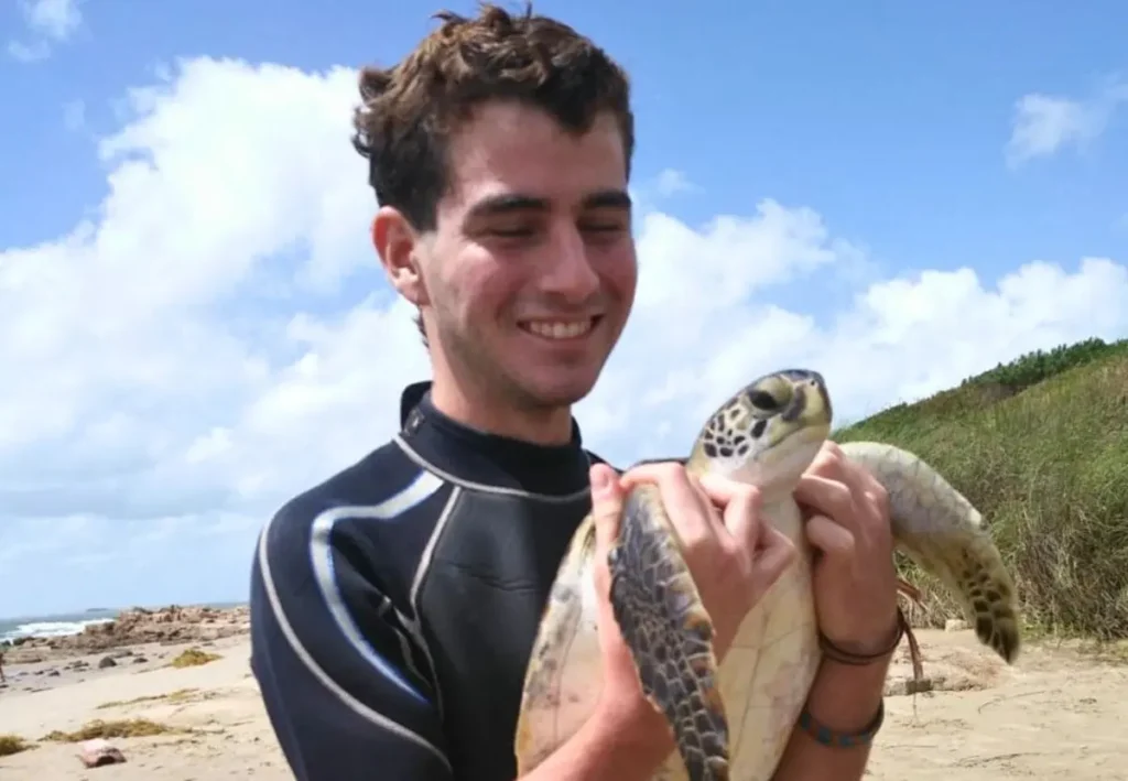 Martín Laspiur sonriendo mientras sostiene una tortuga marina en una jornada de rescate con Karumbé.