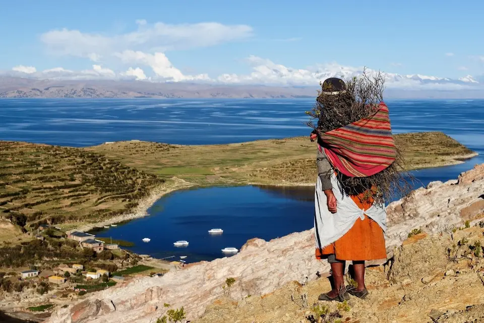 Una mujer indígena contempla el Lago Titicaca, símbolo de la lucha por los derechos de la naturaleza y la identidad cultural.