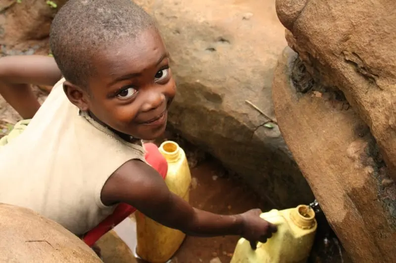 acceso-agua-potable-comunidades-vulnerables | Ambienta Crisis mundial del agua. Joven recogiendo agua de un pozo rudimentario en Uganda.