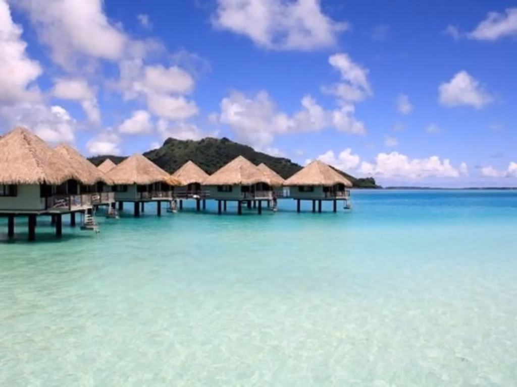 Bungalows sobre agua turquesa en una isla, muestra del cambio climático en el Pacífico y nivel del mar.