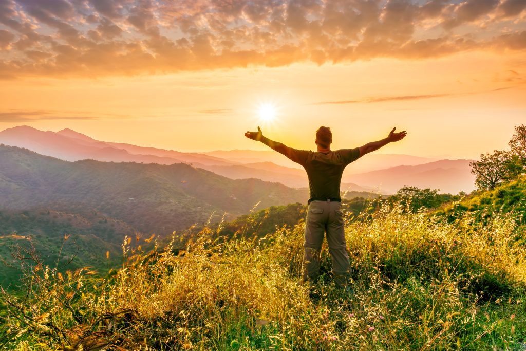 Hombre feliz contemplando un atardecer en la naturaleza.
