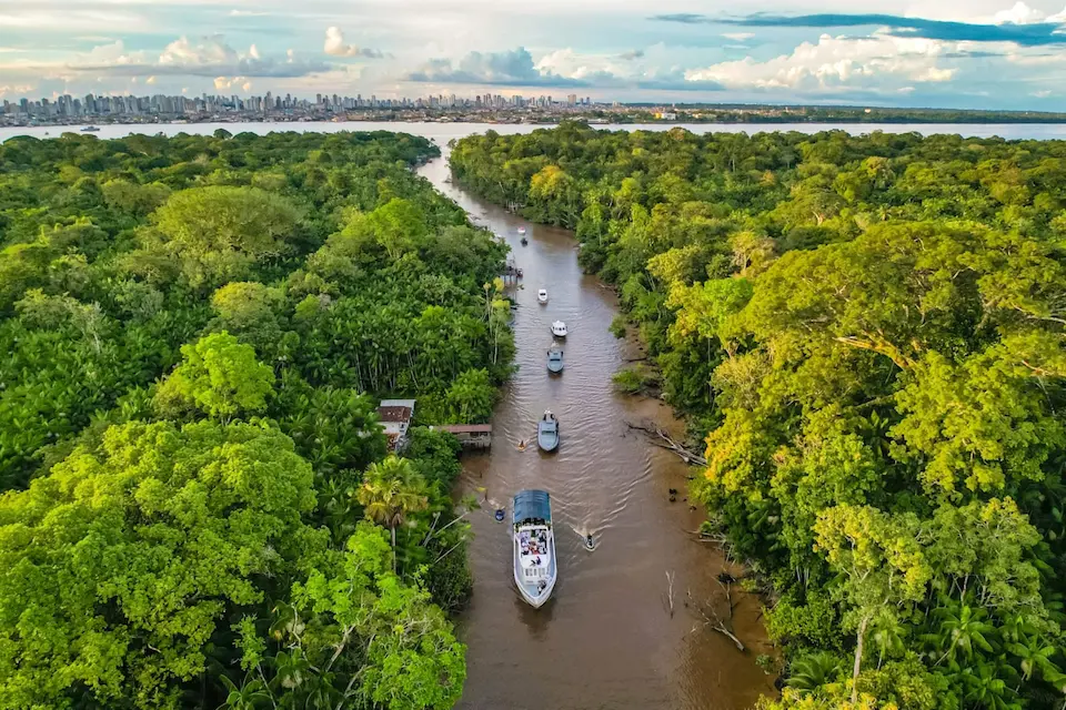 Vista aérea del río Guamá en Belém, con densa selva amazónica y barcos navegando, por Ricardo Stuckert / Agencia Brasil, en el contexto de la COP30.