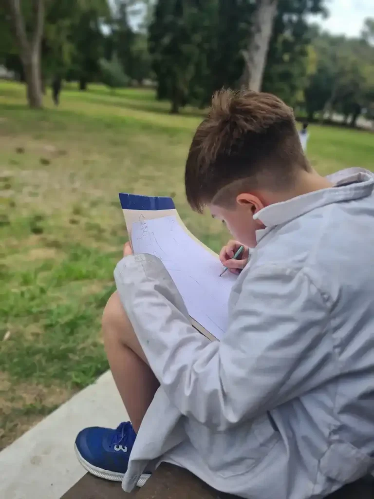 Detalle de un niño de la Escuela 100 registrando observaciones de la naturaleza.