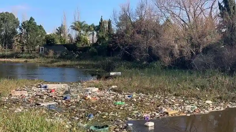 Acumulación crítica de residuos plásticos, basura doméstica y desechos industriales en un tramo urbano del arroyo Carrasco.
