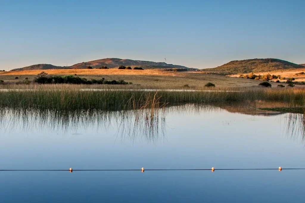 Paisaje del Geoparque Manantiales Serranos con laguna, vegetación nativa y sierras en Lavalleja